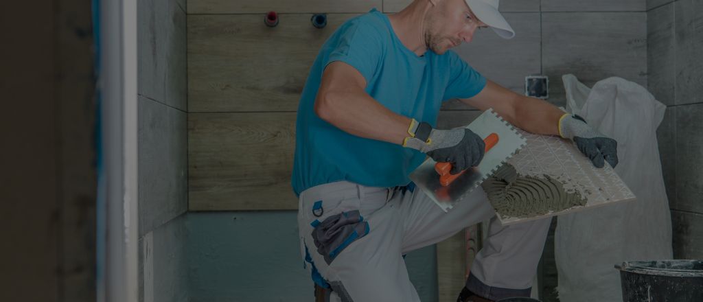 Bathroom renovation in progress with wall tiles being installed by a tiler.