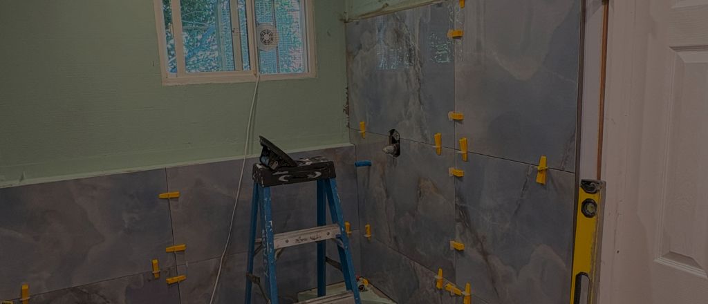Bathroom under renovation with wall tiles partially installed, showing the material selection and installation process.
