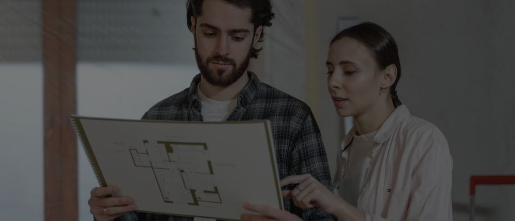 A man and a woman discussing a bathroom renovation plan with design sketches on the table.