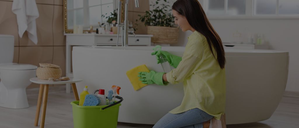 Woman carefully cleaning a luxury bathroom, representing proper maintenance and care for a newly renovated bathroom.